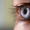 Close-up of a blue eye with prominent eyelashes and detailed iris patterns.